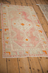 Vintage distressed Oushak runner at an angle, with blush, sea foam green, and tangerine details.