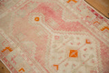 Detail of the abrashed blush and ivory ground on a distressed Oushak rug with tangerine orange accents.