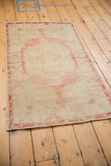 Distressed vintage Oushak rug's faded red border and worn ivory field texture.