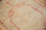 Vintage Oushak runner's textured pile with soft pale cochineal red and ivory patterns.