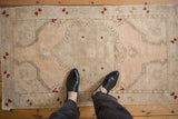 Distressed vintage Oushak rug with faded central design and soft cream, sage, rust tones.