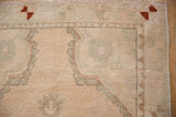 Oushak rug corner with distressed cream pile, dusty sea foam green spandrel, and chestnut rust border.