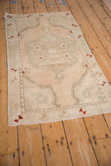 Distressed Oushak rug, faded cream pile with a faded scalloped medallion and floral bouquet.