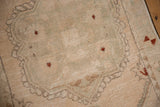 Distressed Oushak rug, cream pile with faded green and rust floral motifs, showing even wear.
