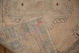 Distressed vintage Turkish Oushak rug corner showing low pile and hand-knotted foundation.
