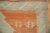 Terracotta and pale slate blue corner of a distressed Kars carpet, featuring saffron starburst motifs.