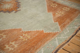 Vintage distressed Turkish Kars carpet detail with faded terracotta, slate blue, and starburst floral motifs.
