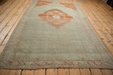 Vintage Distressed Kars carpet corner, showing pale green field, terracotta border, and fringe.