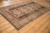 Distressed Anatolian rug corner showing chocolate brown border and faded vine motifs.