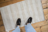 Plain-weave hemp kilim showing soft ivory and beige patterned strips and woven texture.