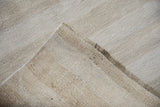 Plain-weave texture and machine-bound edge of the vintage hemp kilim in neutral tones.