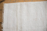 Corner view of a vintage hemp kilim showing its textured plain-weave and bound edge.