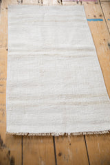 Angled view of the vintage hemp kilim mat highlighting its full length and neutral stripes.