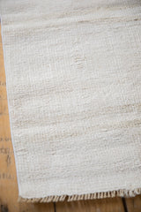 Close-up of the textured plain-weave and secure machine-bound edge of a vintage hemp rug.