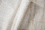 The coarse, plain-weave texture of a folded vintage hemp kilim rug in natural ivory tones.