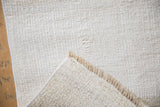 Folded corner of a hemp kilim rug reveals the textured plain-weave and machine-bound edge.