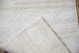 Folded corner showing the hand-woven back and machine-bound edge of a vintage hemp kilim.