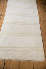 Plain-weave vintage hemp kilim with subtle ivory and beige patterned strips and fringed end.