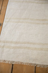Textured plain-weave vintage hemp kilim with neutral patterned strips and fringe.