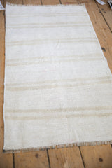 Angled view of a vintage hemp kilim rug highlighting its plain-weave texture and neutral stripes.