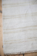 A close view of the nubby, hand-woven texture of a vintage hemp kilim rug.