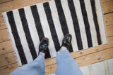 Plain-weave vintage Turkish hemp kilim with charcoal and ivory stripes underfoot.