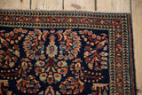 Sarouk rug corner: arabesque, germinating plant borders, and floral bouquets on cobalt blue.