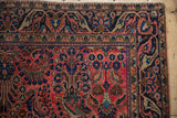 Antique Mohajeran Sarouk rug corner, dusty red floral field, fluid arabesque border, white knots.