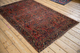 Antique Mohajeran Sarouk rug detail: dusty red rose floral field, sapphire blue arabesque border, white knots.