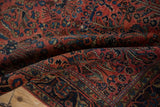 Antique Mohajeran Sarouk rug displaying dusty red floral field, navy arabesque border, and white knot speckling.