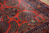 Vintage Sarouk rug's brick red field, sapphire blue palmettes, floral sprays, and navy border.