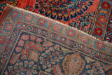 Sarouk rug's folded corner reveals brick red floral pile and blue geometric hand-knotted foundation.