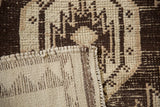Vintage Kurd rug close-up: shorn pile, chocolate brown geometric pattern, and original selvage.