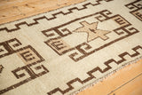 Vintage Kurd runner's ivory and chocolate geometric border, rectilinear motifs, and visible shorn pile.