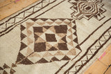 Hand-knotted geometric ivory and dark chocolate patterns on vintage Kurd runner with visible selvage.