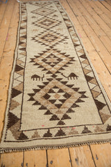 Angled view of a vintage Kurd runner highlighting its repeating geometric medallions and animal figures.