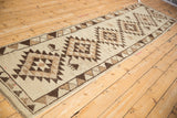 Angled full-length view of a vintage Kurd runner with geometric medallions and animal motifs.