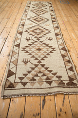 Angled view of a vintage Kurd runner highlighting its repeating serrated gul medallions.
