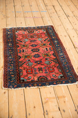 Traditional vintage Lilihan rug with ruby red field and sapphire blue borders, viewed at an angle.