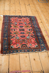 Angled view of a vintage Lilihan rug with a gem-toned floral pattern and worn, tattered ends.