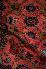 Dense, hand-knotted pile of a folded vintage Lilihan rug with ruby and sapphire floral motifs.