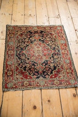 High-angle view of a vintage Josan Sarouk mat showing its floral medallion and navy blue field.