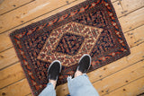 Vintage Senneh rug mat showing the scale of its navy and red Herati pattern.