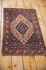 Vintage Senneh rug mat with a navy field and ivory medallion, viewed from above.