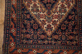 Detailed view of the vintage Senneh's stepped corner spandrel and navy Herati patterned field.