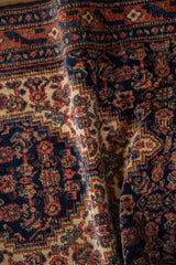 Draped vintage Senneh rug showing its dense pile texture and intricate Herati design motifs.
