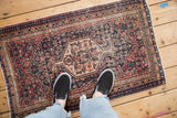 Antique Senneh rug's navy, brick red, and beige Herati motif and medallion, showing wear to foundation.