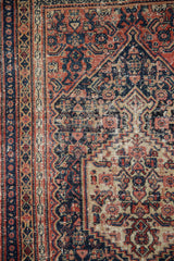 Antique Senneh rug's navy, brick red geometric border and Herati motif field with wear.