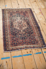 Antique Senneh rug corner with navy, brick red Herati motif, serrated delineation, tattered edge.