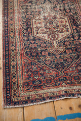 Antique Senneh rug corner revealing worn Herati motifs, missing selvedge, and tattered fringe.